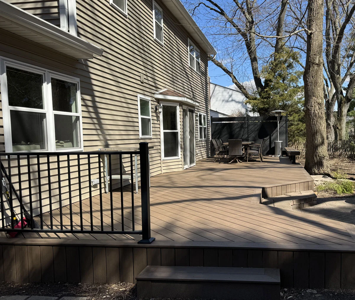 Composite Deck With Black Railings And Patio Furniture In Early Spring