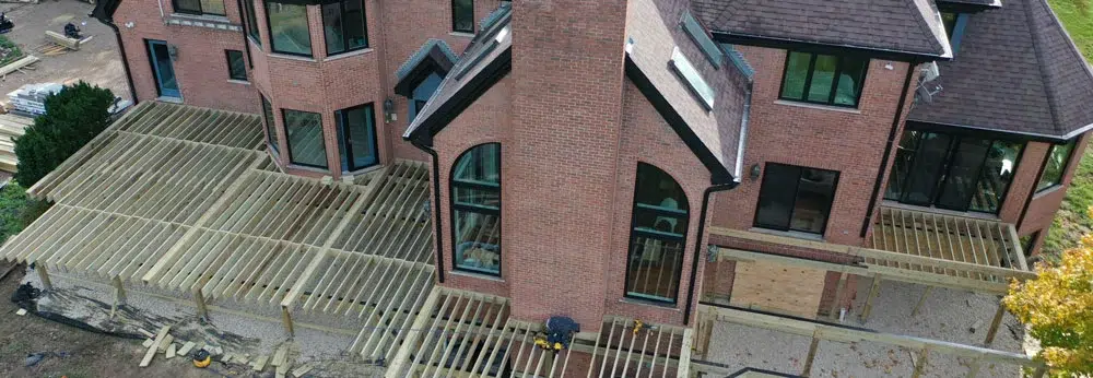 Royal Deck Construction Project Showing Large-Scale Deck Frame Installation Adjacent To Residential Brick Home