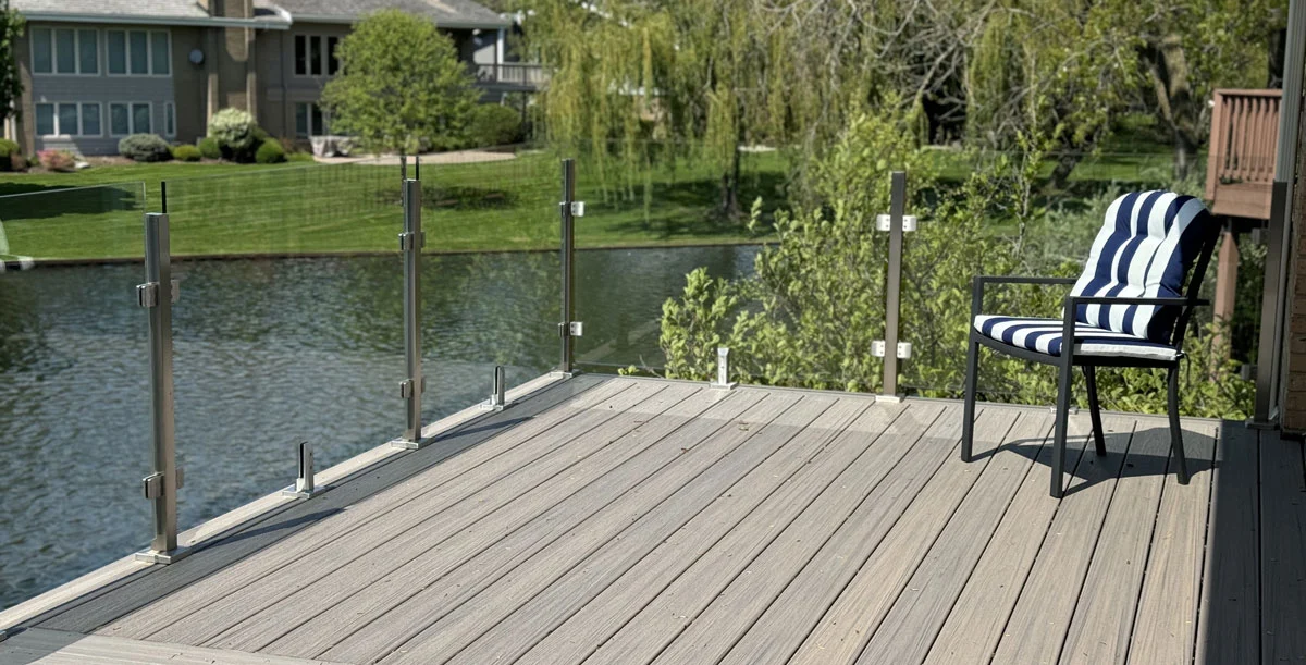 Frameless Glass Panel Railing On A Composite Deck Overlooking A Pond